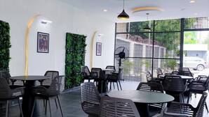 A modern indoor dining area with round tables and black chairs, featuring recessed lighting and green wall accents. - Saint Tropez Hotel and Suites (Abuja)