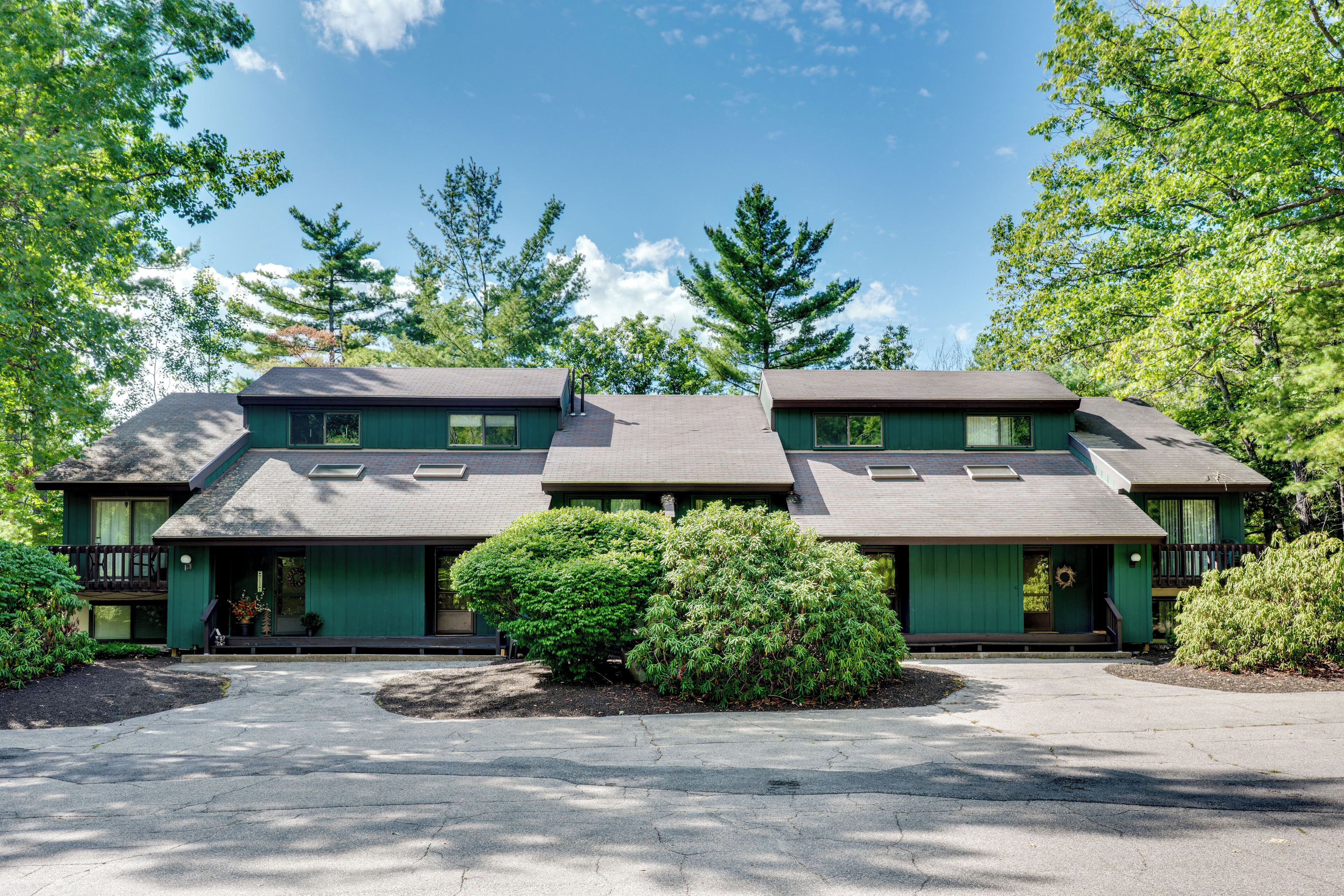 A two-story building with a green exterior and a driveway leading to the entrance.