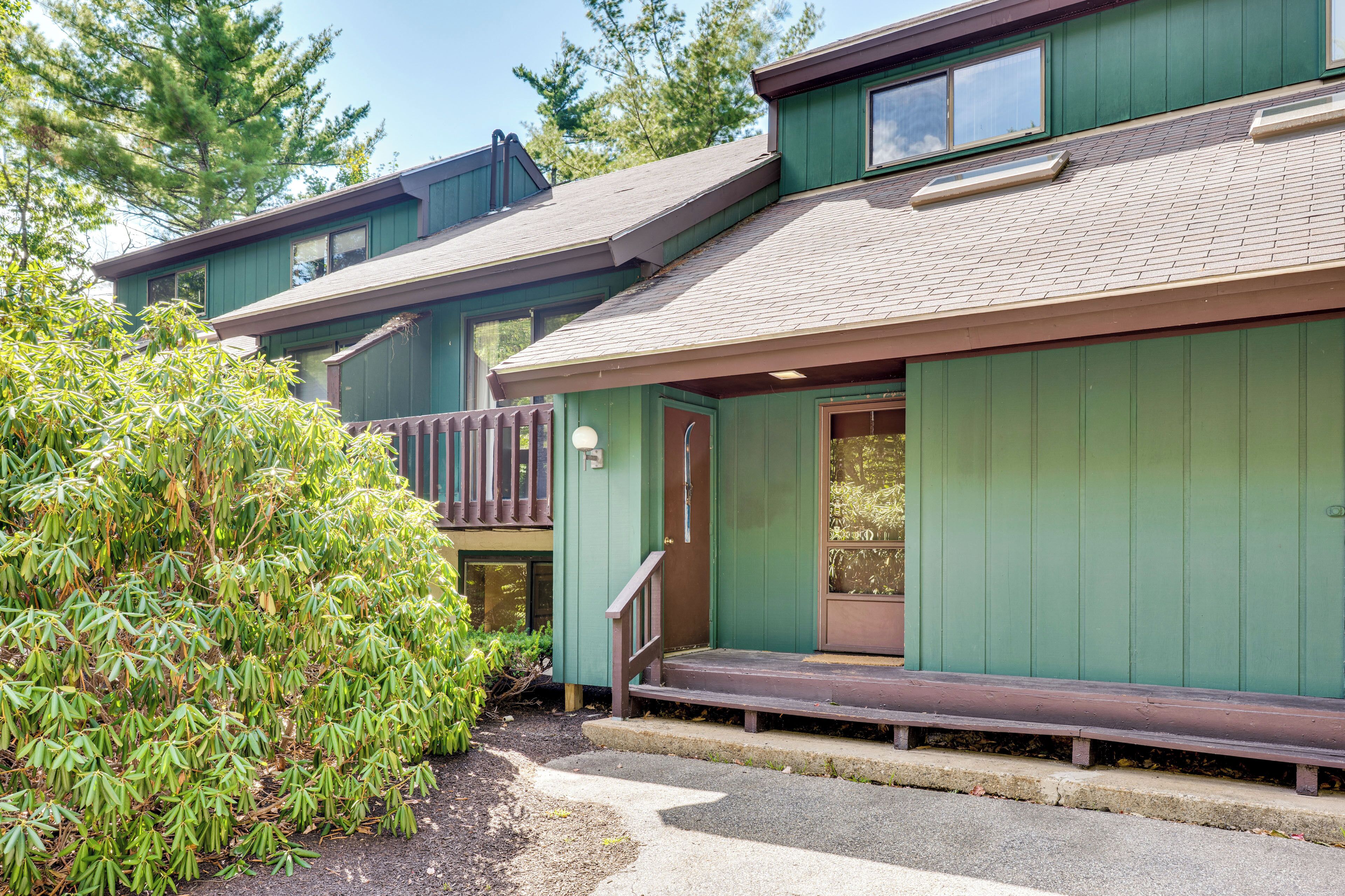 A two-story building with a green exterior, a front porch, and a visible staircase leading to the second floor.