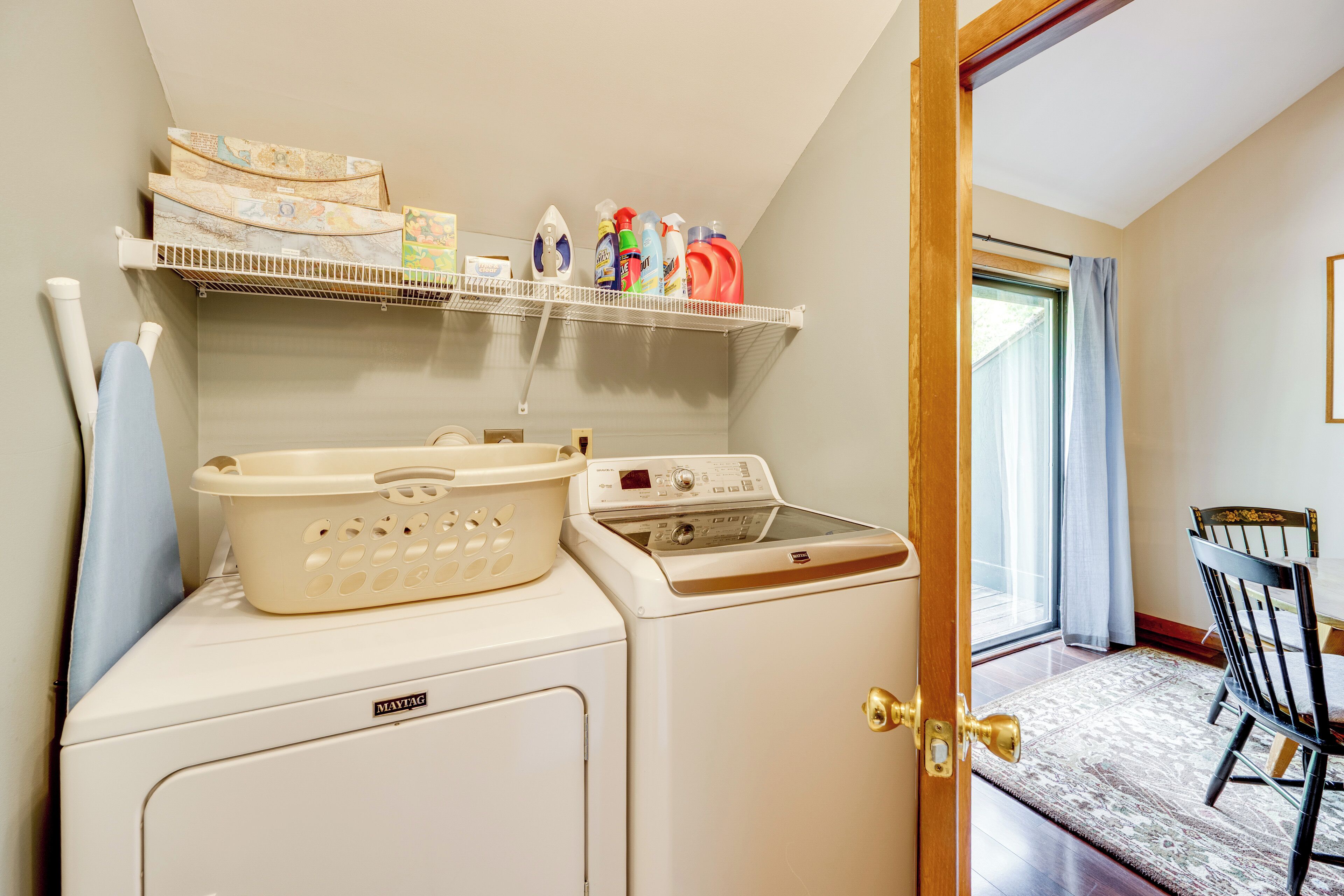 Un espace buanderie équipé d’un lave-linge, d’un sèche-linge et d’étagères où sont rangés les produits de lessive.