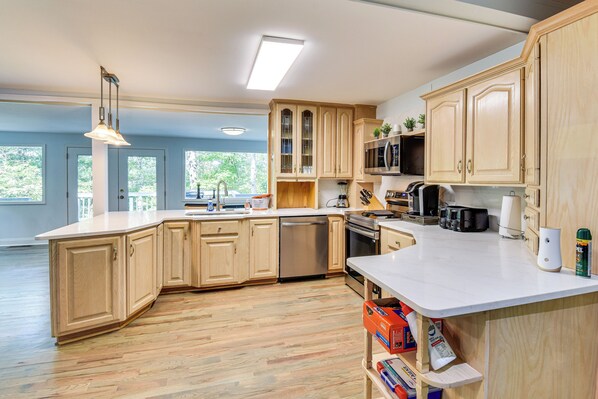 A spacious kitchen with wooden cabinets, a large island, and modern appliances. - Woodsy Retreat w/ Deck & Views in Dahlonega! (Dahlonega)