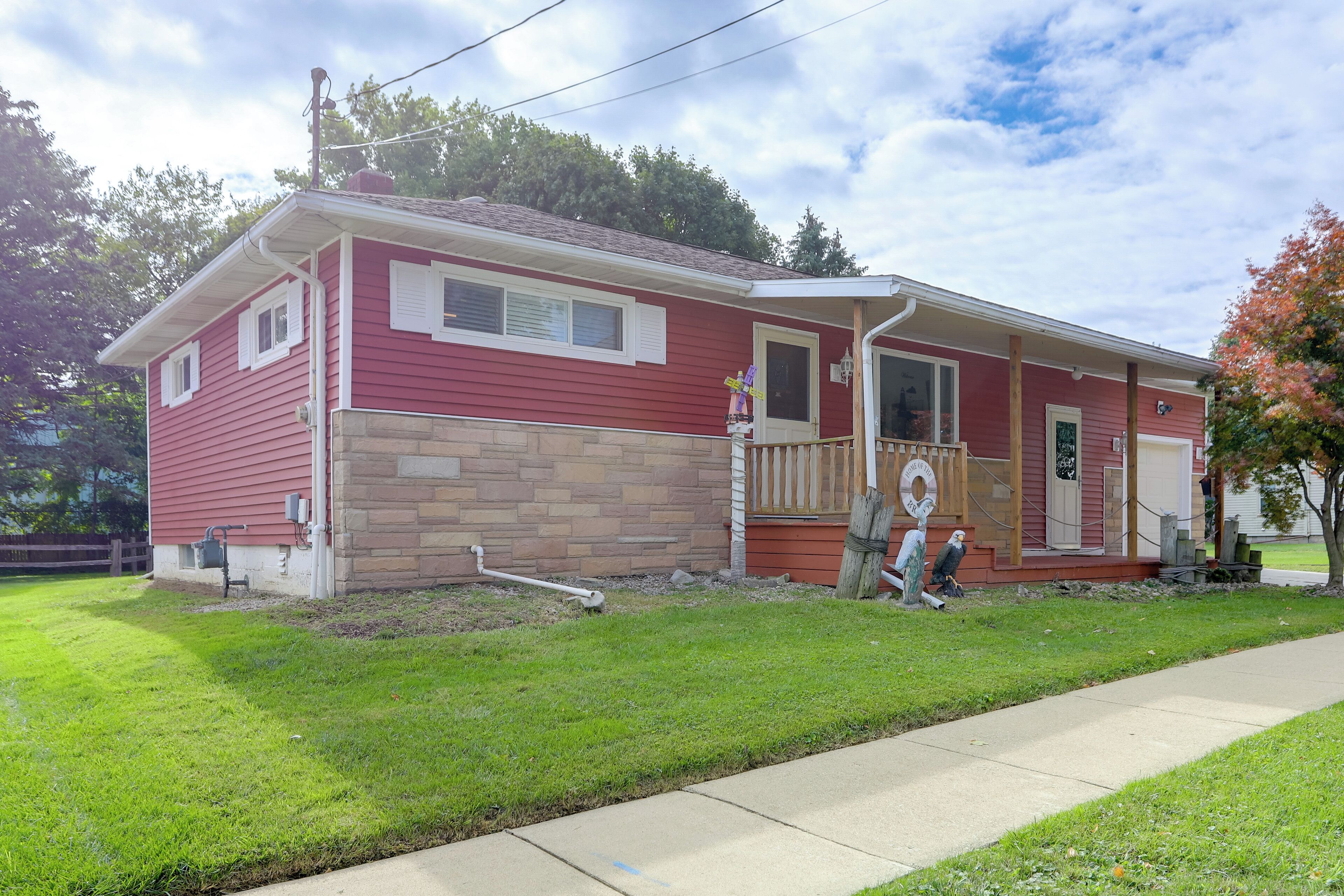 A two-story house with a red exterior and a stone foundation.