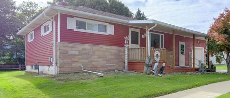 A two-story house with a red exterior and a stone foundation.