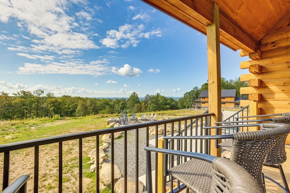 A wooden deck with wicker chairs and a view of a grassy area and trees.