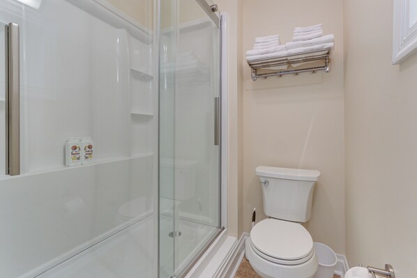 A bathroom with a glass-enclosed shower, a toilet, and a towel rack with folded towels. - Golf Course Guest Suite in Gettysburg (Gettysburg)