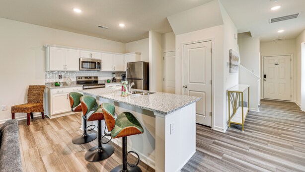 A modern kitchen with white cabinetry, a granite countertop, and a central island with bar stools. - Screened Patio: Townhome 3 Mi to Dtwn Wilson! (Wilson)