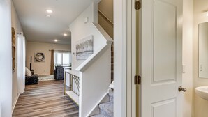 A hallway with a wooden floor, a staircase with white railings, and a door with a gold handle. - Screened Patio: Townhome 3 Mi to Dtwn Wilson! (Wilson)