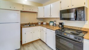 Una cocina con armarios blancos, una estufa de acero inoxidable, un microondas y un lavavajillas.
