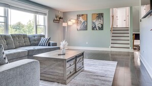 En moderne stue med en hjørnesofa, et træsofabord og kunst på væggene.