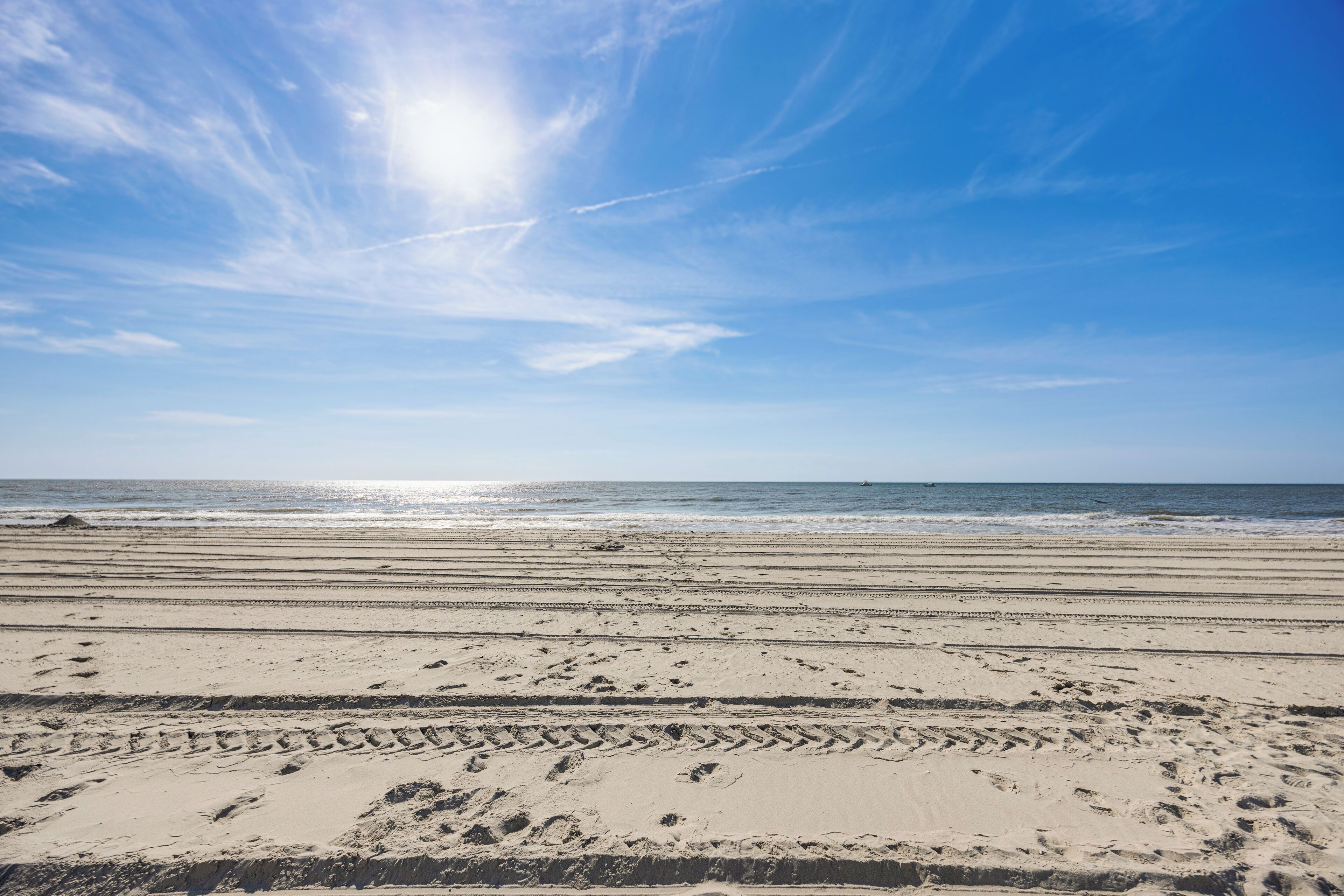 A beach with footprints and a clear sky.