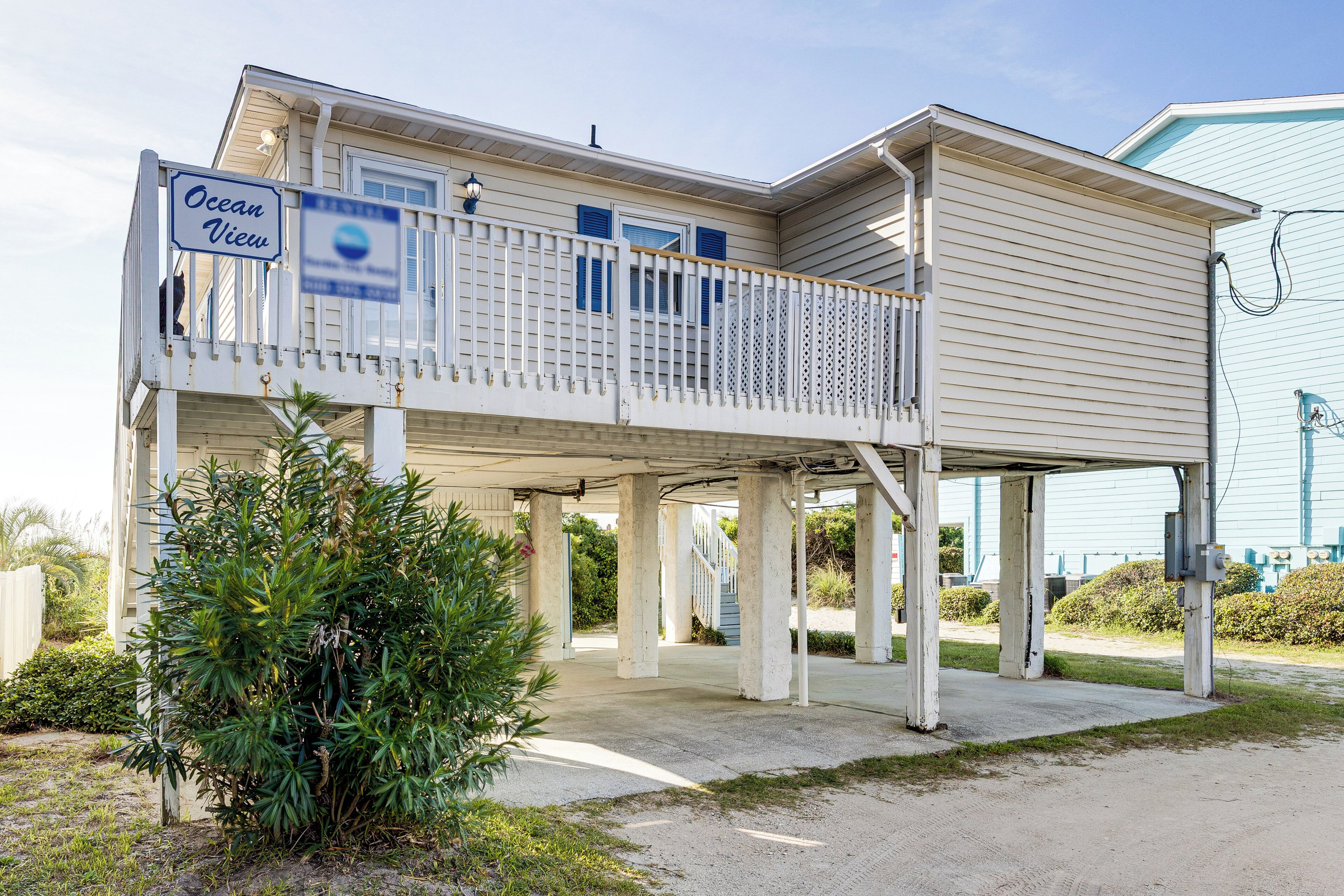 A two-story house with a balcony, a sign reading "Ocean View," and a covered porch area.