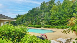 A backyard with a swimming pool, surrounded by lush greenery and a covered seating area. - 2 Mi to Tiger Territory! Condo w/ Community Pool (Auburn)