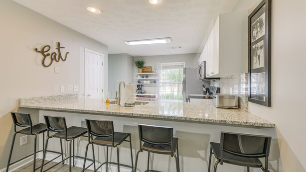 A kitchen with a large island, bar stools, and a 'Eat' sign on the wall. - 2 Mi to Tiger Territory! Condo w/ Community Pool (Auburn)