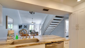 A modern kitchen with a large island, white cabinetry, and a stainless steel dishwasher.