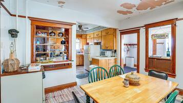 A kitchen with wooden cabinets, a dining table, chairs, and a refrigerator.