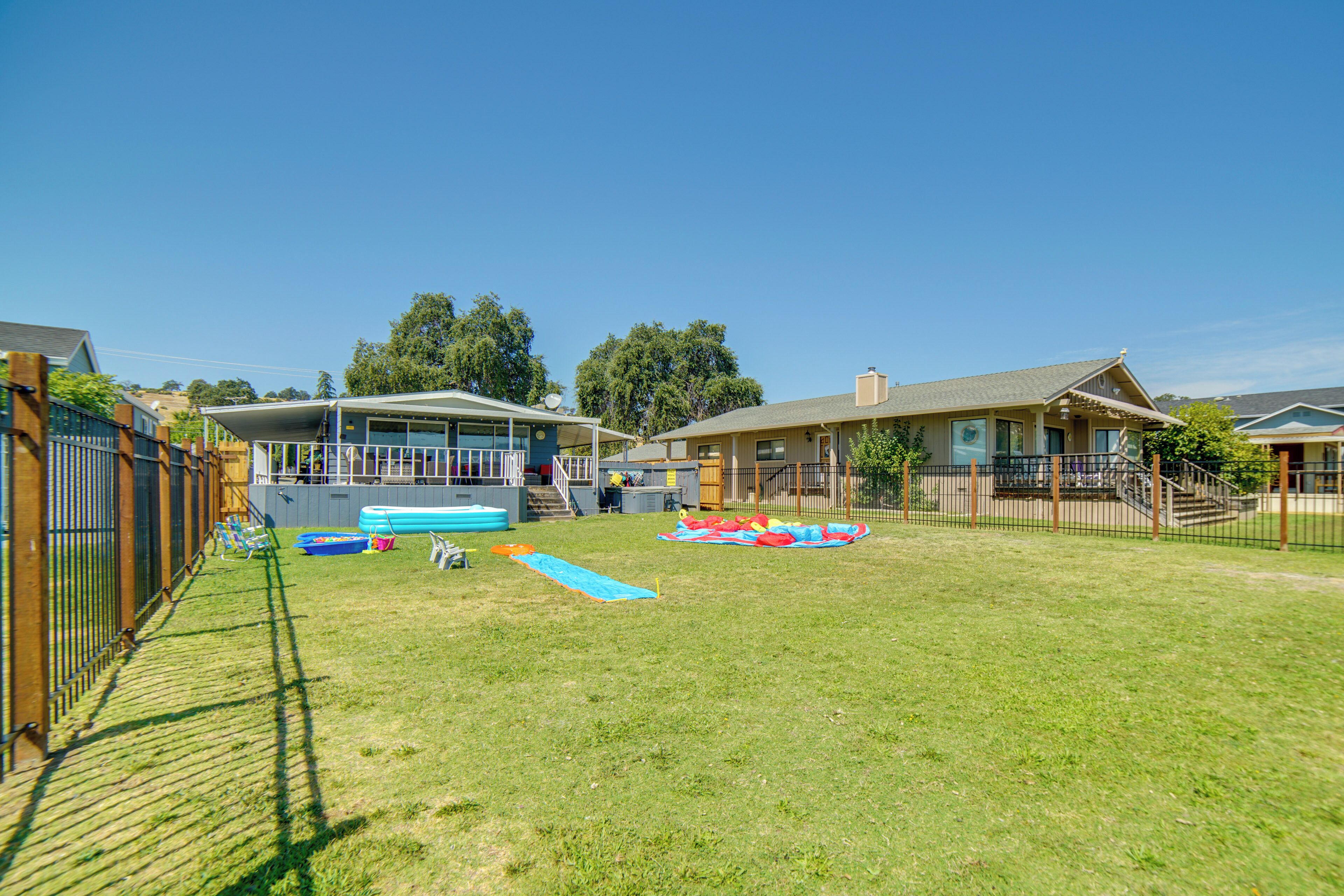A residential backyard with a swimming pool, inflatable slides, and a fenced area.