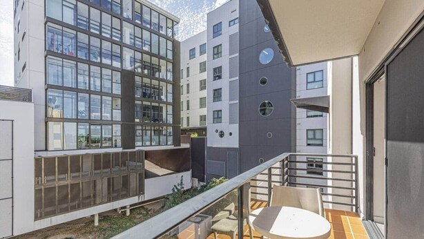 Un edificio moderno con ventanas amplias, un balcón con sillas y un suelo de baldosas.