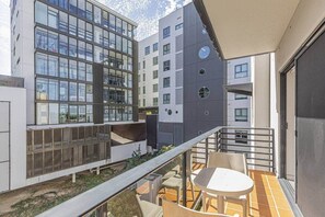 A modern building with large windows, a balcony with chairs, and a tiled floor. - City Lights Retreats - 2 Bedroom, 1 Bathroom (Perth)