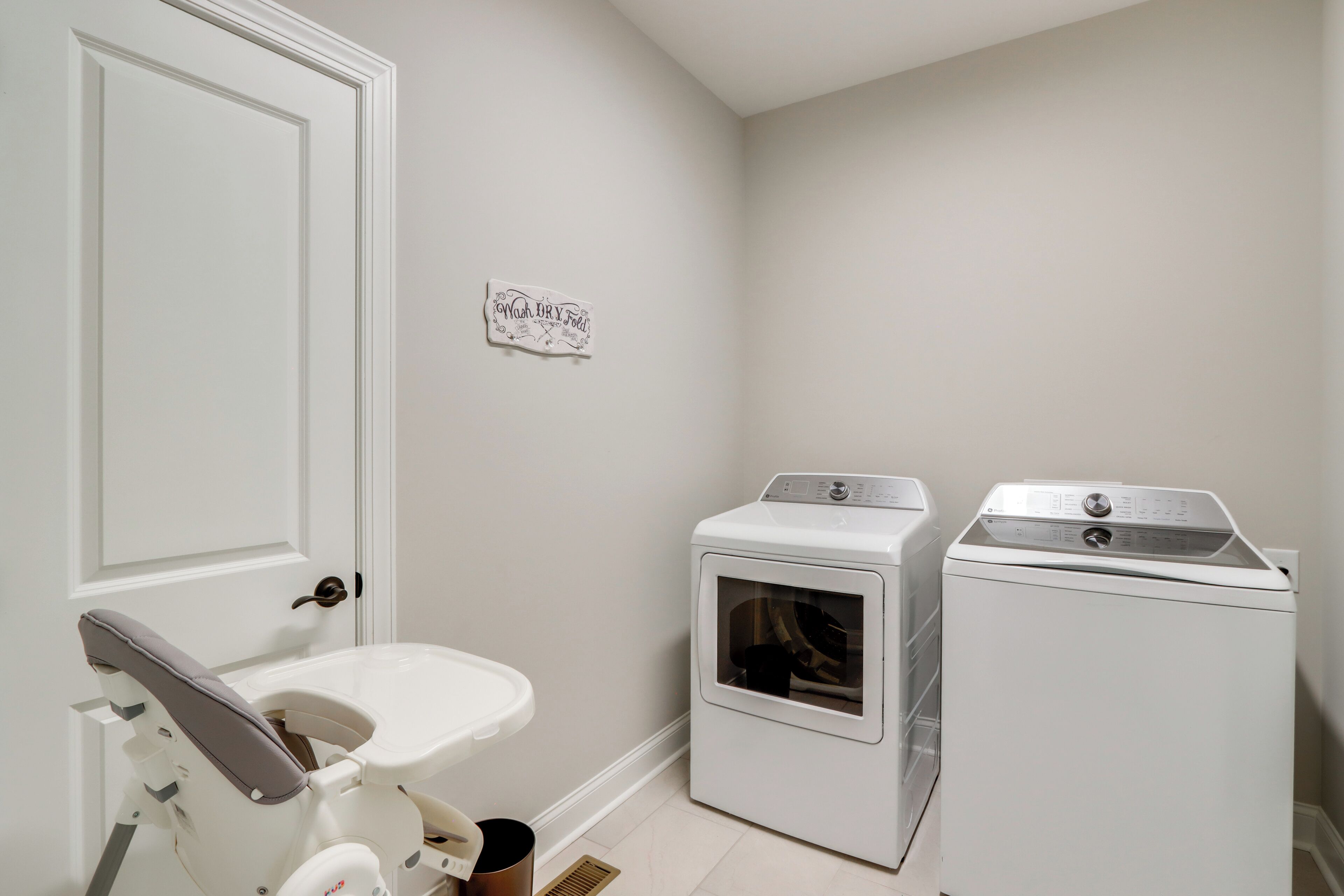A laundry room with a white door, a washing machine, and a dryer.