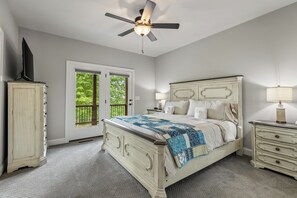 A bedroom with a bed, a nightstand, a dresser, a ceiling fan, and a door leading to a balcony.