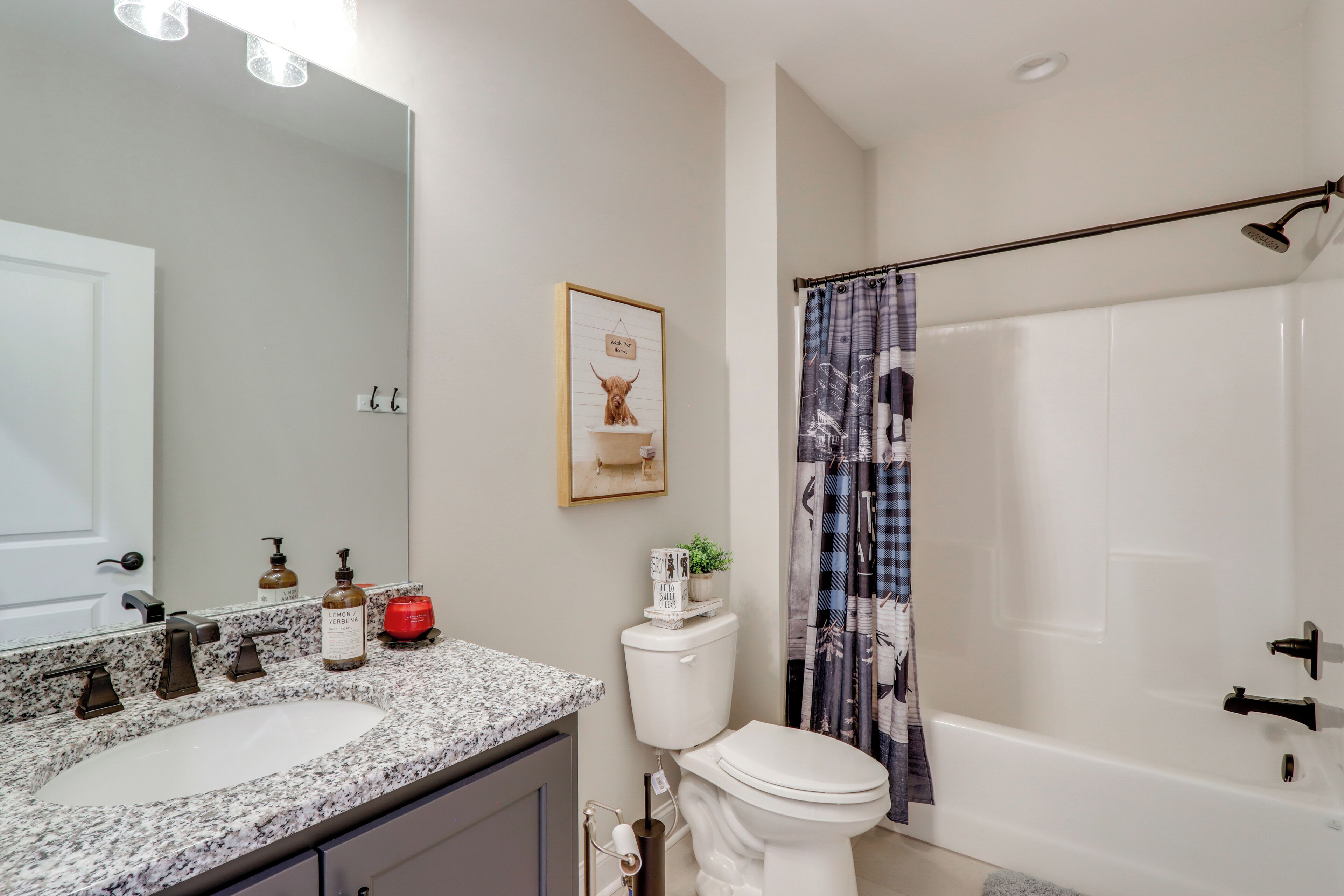 A bathroom with a granite sink, white toilet, and a shower with a curtain.