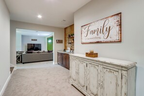 A spacious living area with a large white cabinet, a sofa, and a wall sign that reads "Family is everything." - Cozy Blue Ridge Cabin: Game Room & Mountain Views (Blairsville)