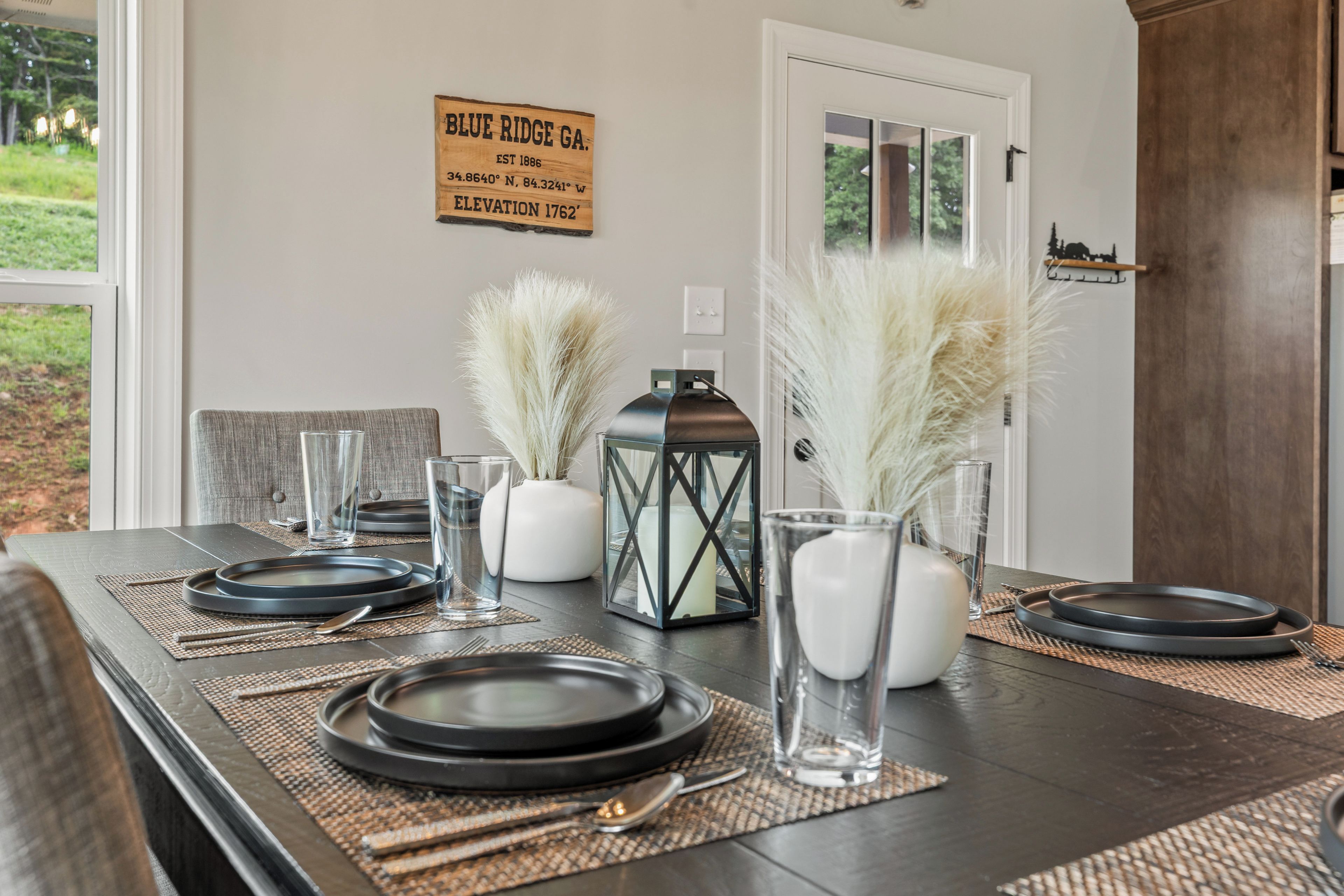 A dining table set with plates, glasses, and a lantern.