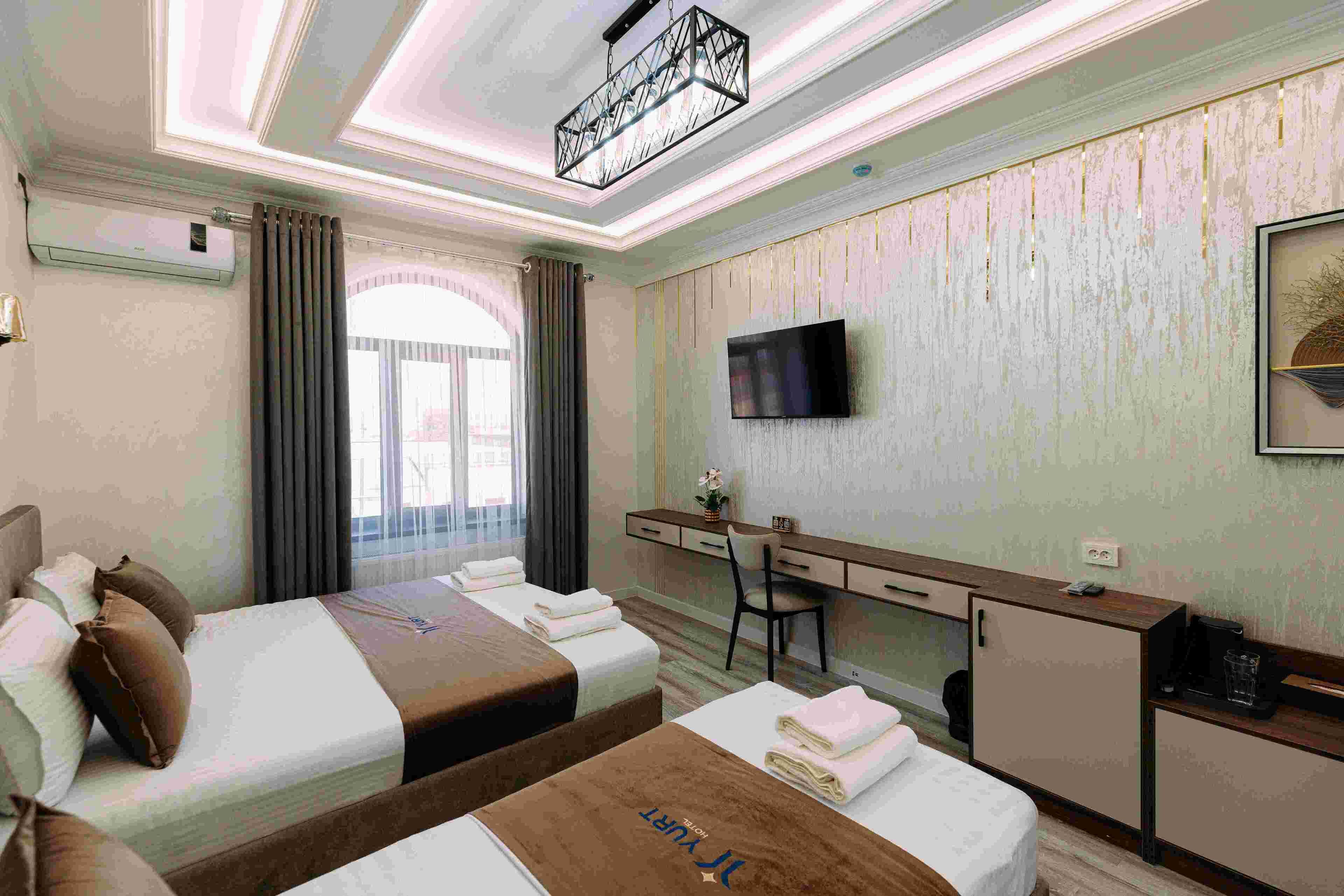 Habitación de hotel con dos camas, un escritorio, una silla, un televisor y un minibar.