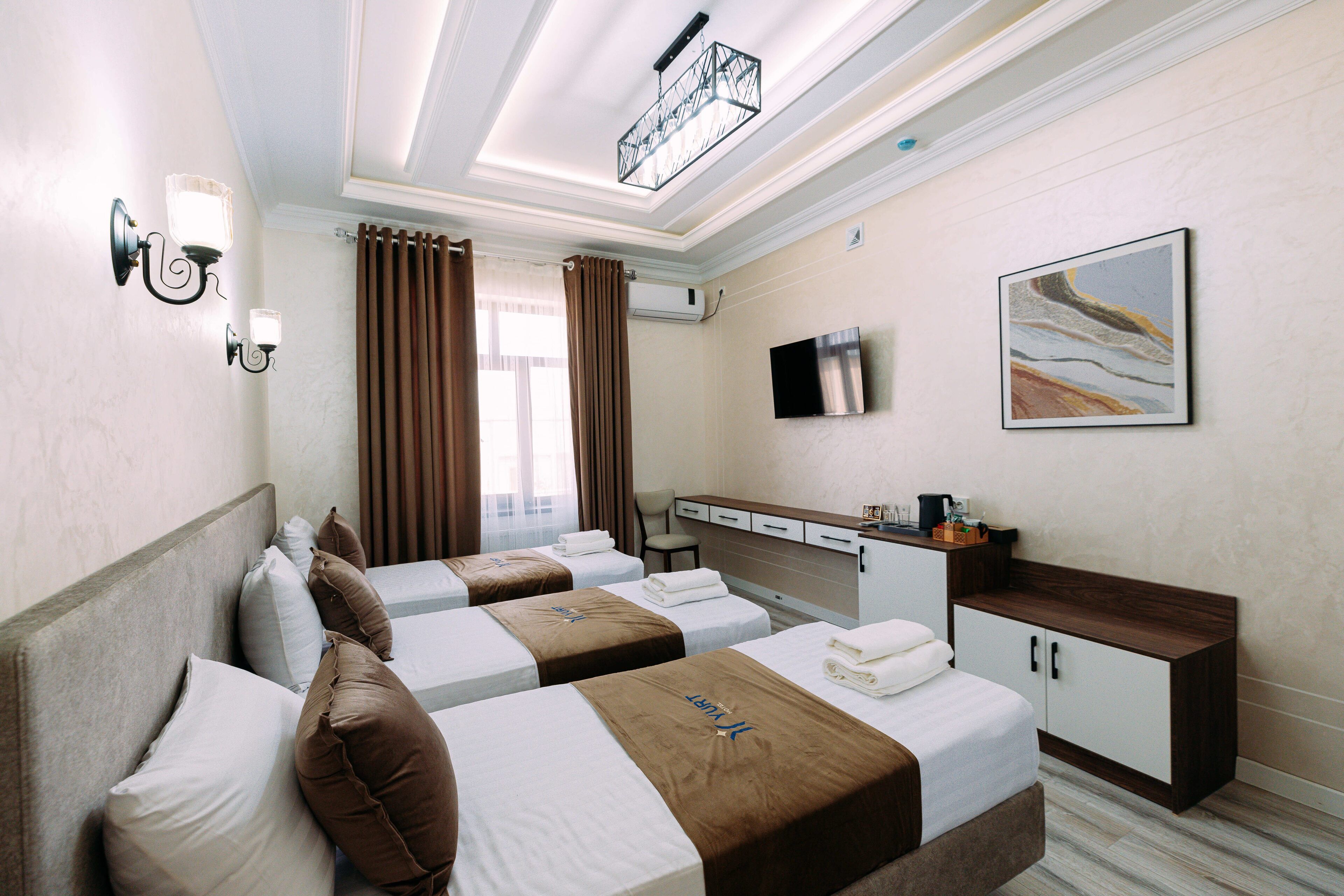 A hotel room with two beds, a desk, a TV, and a painting on the wall.
