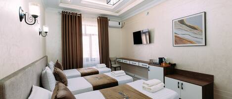 A hotel room with two beds, a desk, a TV, and a painting on the wall.