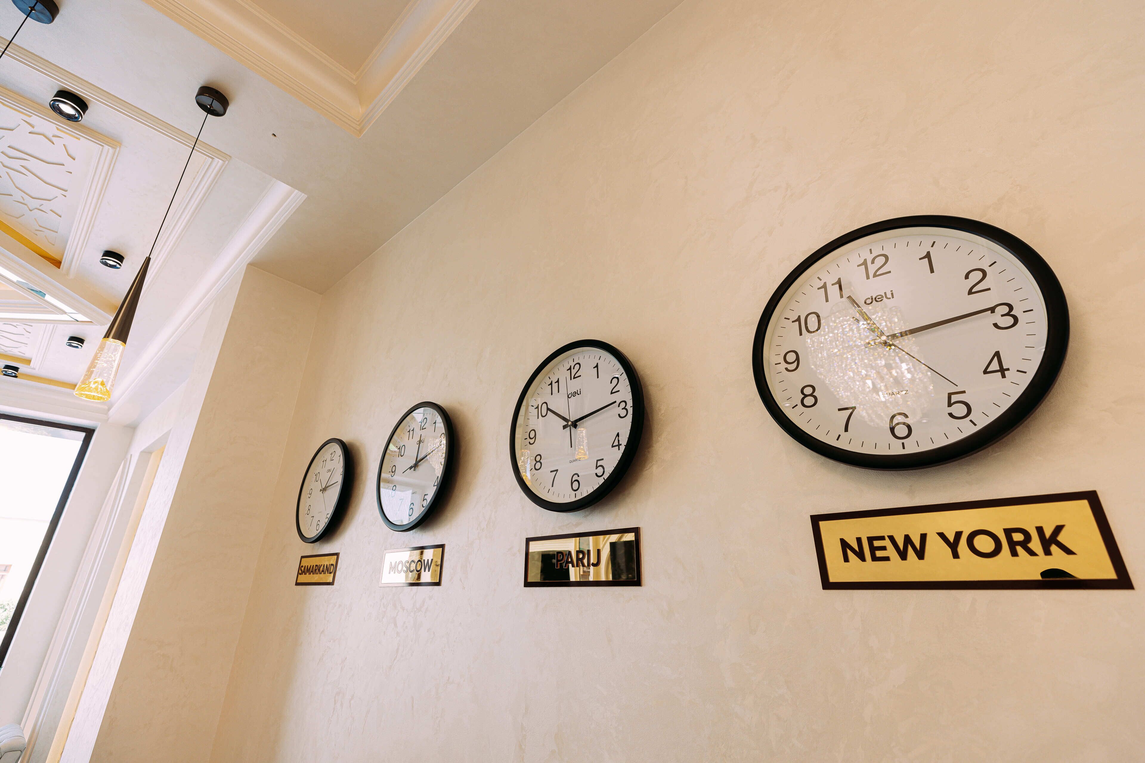 Four clocks on a wall, each with a city name below it.