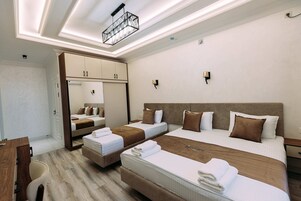 Habitación de hotel con dos camas, un escritorio, una silla, un armario y una lámpara en el techo.