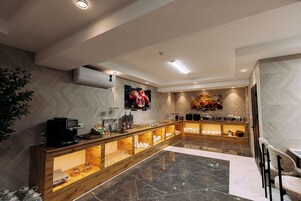 Un moderno vestíbulo de hotel con piso de mármol, una recepción de madera y una máquina de café.