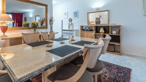 A modern dining area with a marble table, cushioned chairs, and a patterned rug.