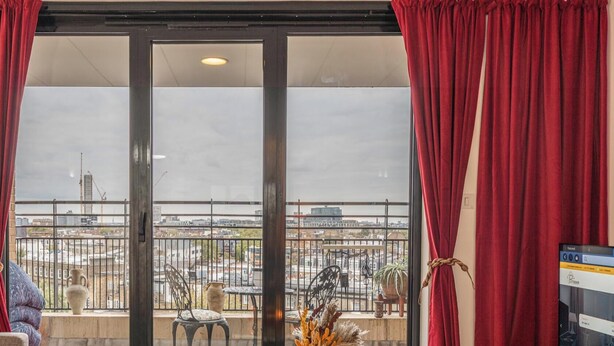 A room with a balcony, a table with candles, and a TV on a wooden stand.