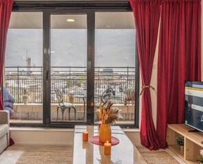 A room with a balcony, a table with candles, and a TV on a wooden stand.