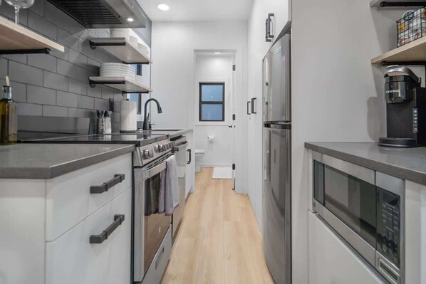 Una cocina moderna con electrodomésticos de acero inoxidable, horno empotrado y cafetera.