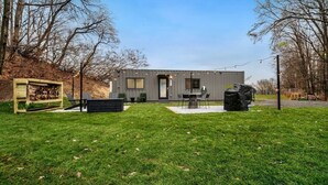 A modern house with a patio area, a fire pit, and a large stone sculpture.