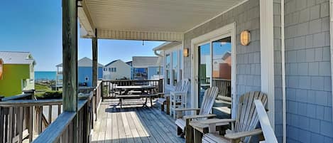 Una terraza de madera con mobiliario exterior y vista al océano.