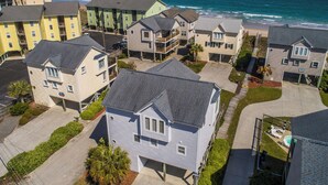 A coastal residential area with multiple two-story houses, some with balconies, and a clear view of the ocean. - Song of the Sea | Pet-Friendly, Spacious Home w/Easy Beach Access (Surf City)