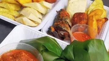 A meal with fried items, potato wedges, and a side of sauce.
