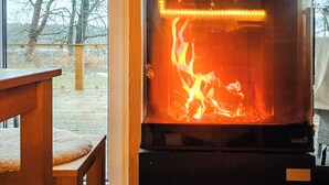 Una cocina moderna con un horno de leña empotrado, una mesa de comedor y vistas a árboles.