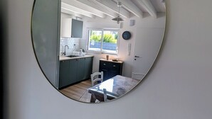 A modern kitchen with a window, a dining area with a table and chairs, and a white ceiling with exposed beams. - House with garden, walking distance to the beach (Pornichet)