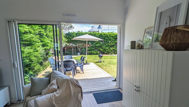 A modern living room with a large sliding glass door leading to an outdoor patio area. - House with garden, walking distance to the beach (Pornichet)