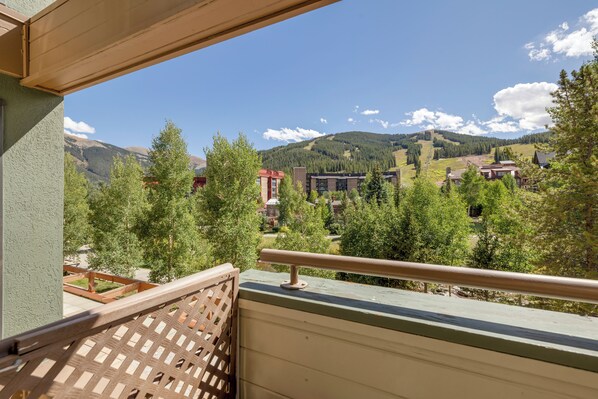A balcony with a view of a mountainous landscape, buildings, and trees. - Heart of Copper with Amazing Views (Frisco)