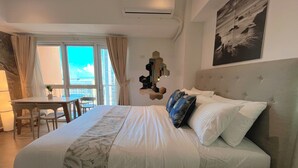 A bedroom with a large bed, a dining table, and chairs in the adjacent area. - BGC 1BR, Steps to Venice Mall, 300Mbps Fiber 16K (Taguig)