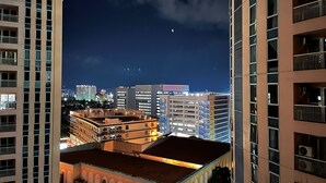 A nighttime cityscape with high-rise buildings and a visible moon. - BGC 1BR, Steps to Venice Mall, 300Mbps Fiber 16K (Taguig)