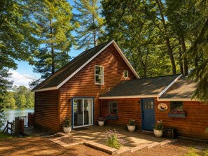 A wooden cabin with a porch, a sliding glass door, and a small deck.