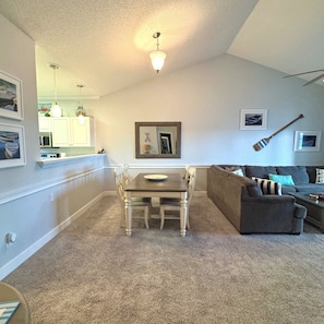 A dining area with a table and chairs, a couch, and a ceiling light.