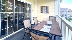 An outdoor patio with a table and chairs, a ceiling fan, and a view of a residential area. - Pet Friendly 2BR Condo, Spacious w/ Vaulted Ceilings! (Little River)